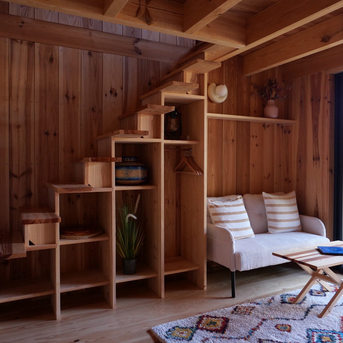 Séjour d'un cabanon : escalier-bibliothèque en pin et canapé